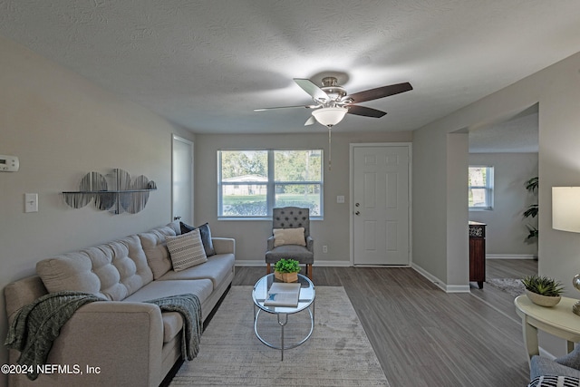 living room featuring ceiling fan, a healthy amount of sunlight, wood-type flooring, and a textured ceiling