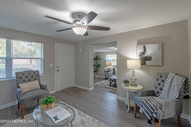 living area with wood-type flooring, a textured ceiling, and ceiling fan