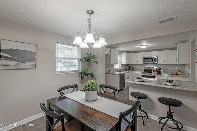 dining space featuring dark hardwood / wood-style floors, sink, a textured ceiling, and an inviting chandelier