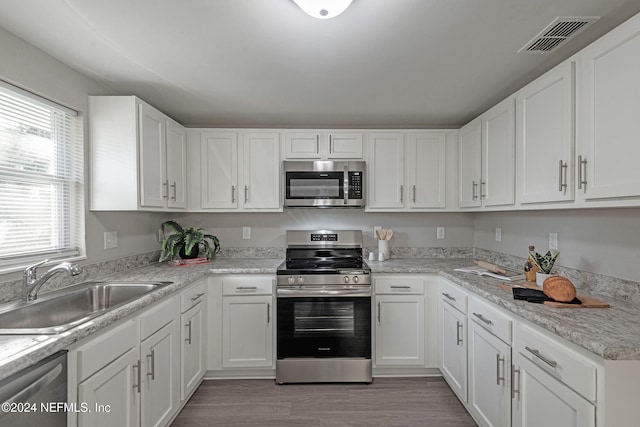 kitchen featuring white cabinets, sink, stainless steel appliances, and light hardwood / wood-style flooring