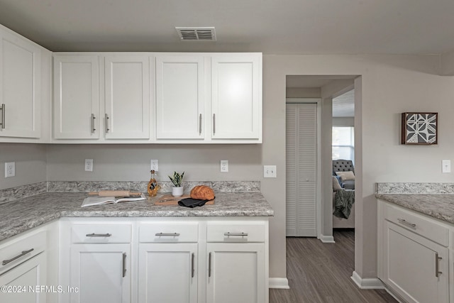 kitchen with white cabinets, dark hardwood / wood-style flooring, and light stone countertops