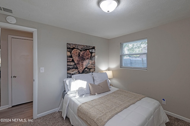 bedroom with wood-type flooring and a textured ceiling