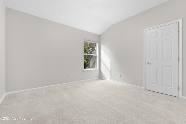 carpeted spare room featuring lofted ceiling