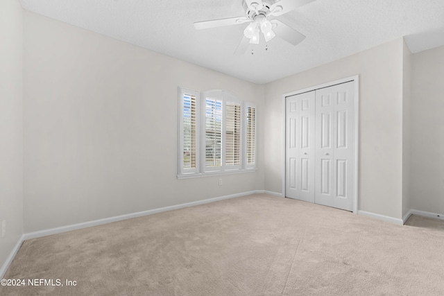 unfurnished bedroom featuring ceiling fan, a closet, and light colored carpet