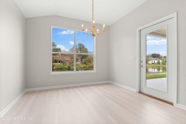 spare room featuring a chandelier, a water view, light hardwood / wood-style floors, and lofted ceiling