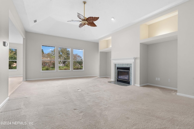 unfurnished living room featuring ceiling fan, light colored carpet, and a high end fireplace