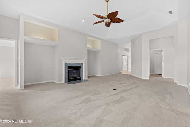 unfurnished living room with a high end fireplace, light carpet, ceiling fan, and a high ceiling