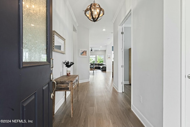 corridor with dark hardwood / wood-style flooring, crown molding, and a notable chandelier