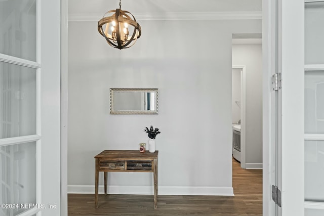 corridor with dark hardwood / wood-style flooring, an inviting chandelier, and ornamental molding