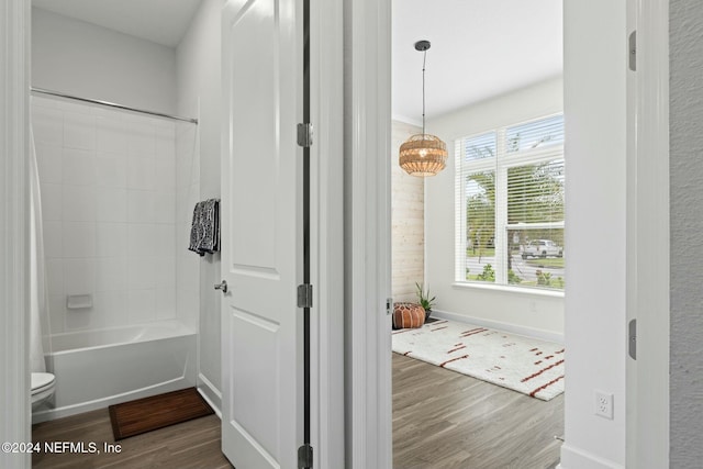 bathroom with hardwood / wood-style floors,  shower combination, and toilet