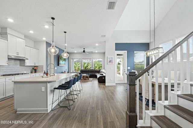 kitchen with ceiling fan, sink, dark hardwood / wood-style floors, pendant lighting, and a center island with sink