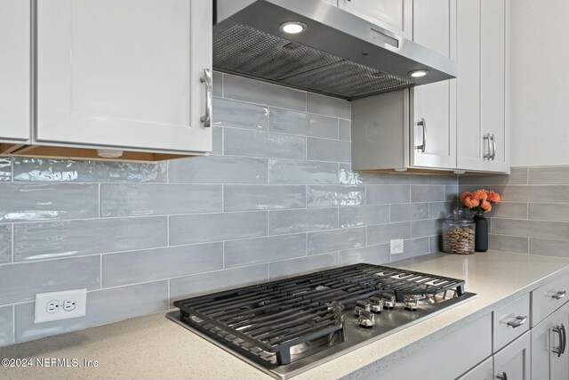 kitchen with decorative backsplash, white cabinetry, extractor fan, and stainless steel gas cooktop