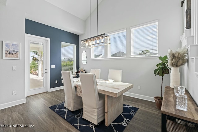 dining space with dark hardwood / wood-style flooring, lofted ceiling, and an inviting chandelier