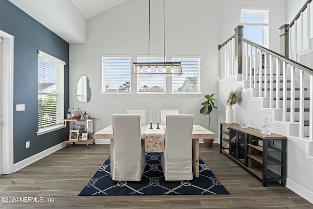 dining space with high vaulted ceiling, plenty of natural light, dark wood-type flooring, and a notable chandelier