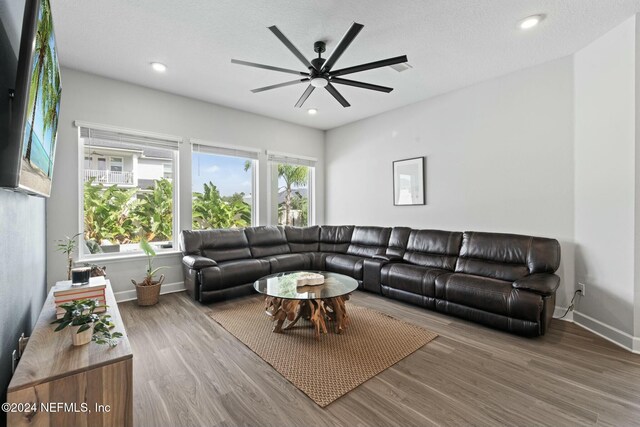 living room with hardwood / wood-style flooring, ceiling fan, and a textured ceiling