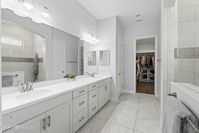 bathroom with tile patterned floors, vanity, and a tile shower