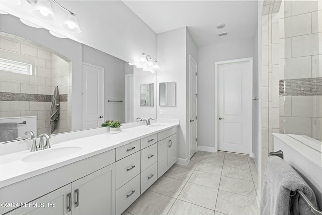 bathroom with tile patterned flooring, vanity, and tiled shower