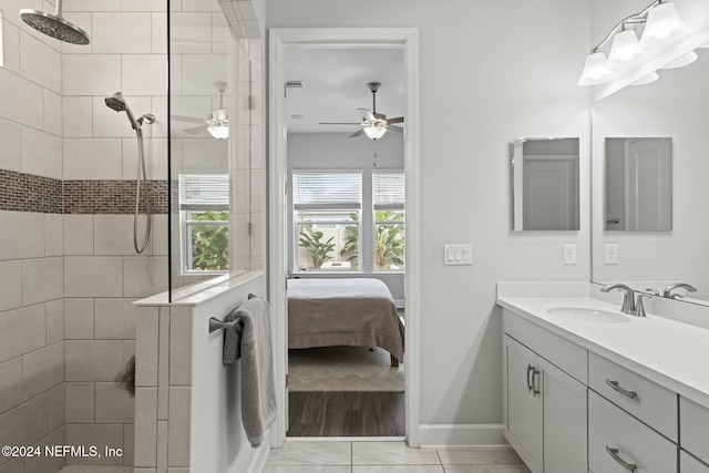 bathroom with tiled shower, vanity, ceiling fan, and tile patterned flooring