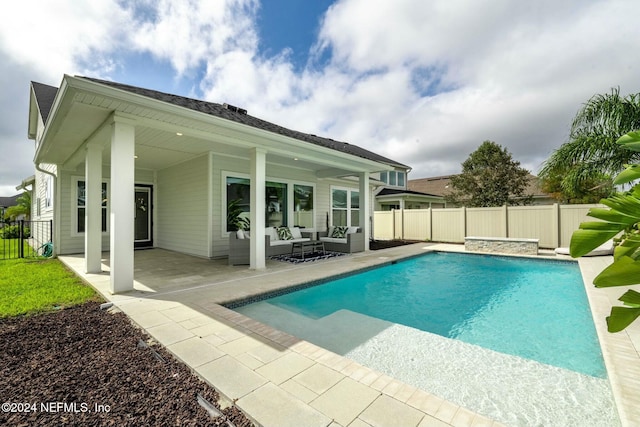 back of house with an outdoor living space, a fenced in pool, and a patio area