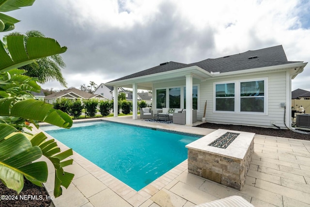 view of pool featuring cooling unit, an outdoor living space with a fire pit, and a patio