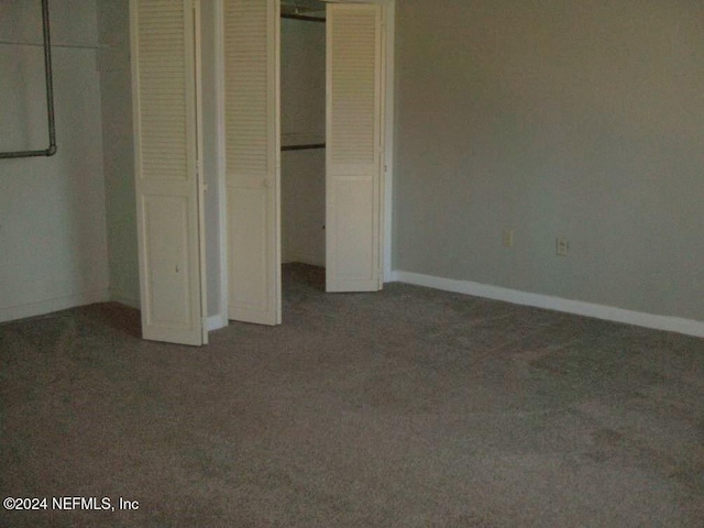 unfurnished bedroom featuring a closet and dark colored carpet