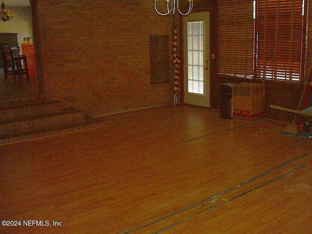 empty room featuring wood-type flooring and an inviting chandelier