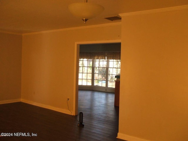 empty room featuring crown molding and dark wood-type flooring