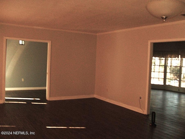 empty room featuring dark wood-type flooring and ornamental molding