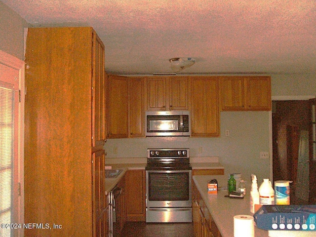 kitchen with a textured ceiling and appliances with stainless steel finishes