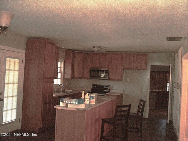 kitchen with range with electric cooktop, sink, a kitchen island, and a textured ceiling