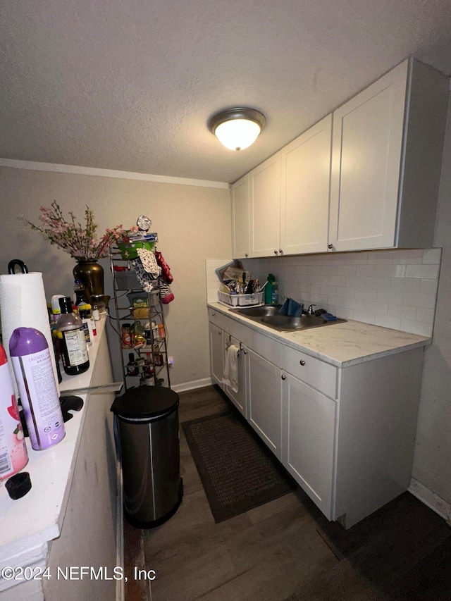 laundry room with a textured ceiling, dark hardwood / wood-style floors, crown molding, and sink