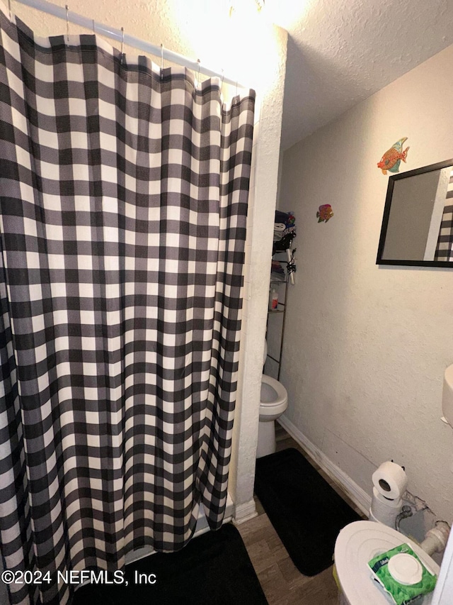 bathroom with hardwood / wood-style flooring, toilet, and a textured ceiling