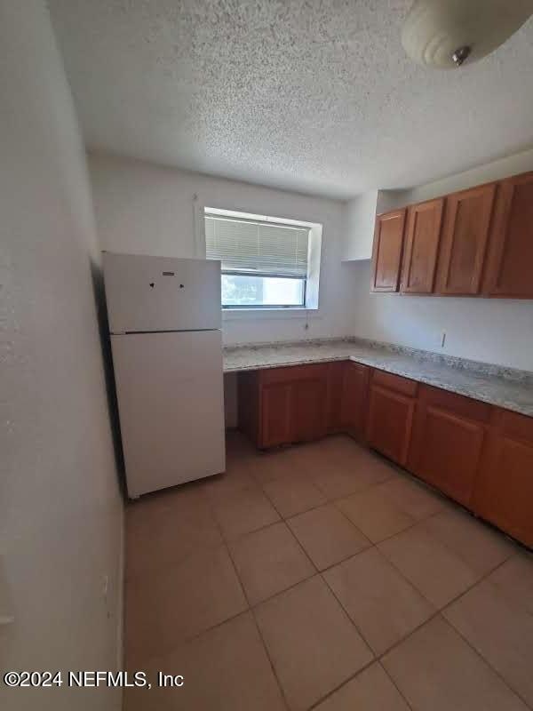 kitchen with white refrigerator, light tile patterned floors, and a textured ceiling