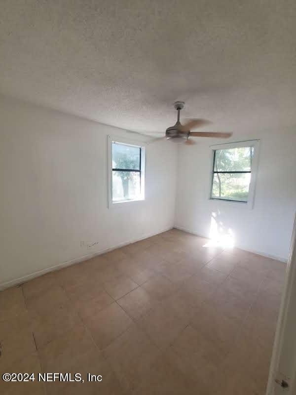 spare room featuring a wealth of natural light, ceiling fan, and a textured ceiling