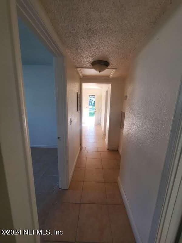 corridor featuring light tile patterned flooring and a textured ceiling