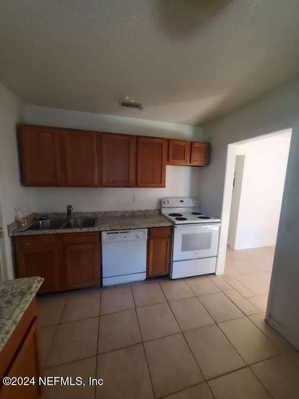 kitchen with light tile patterned flooring, white appliances, and sink