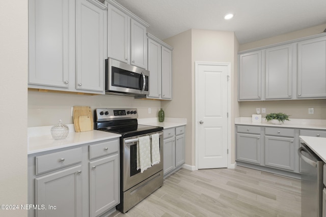 kitchen with gray cabinets, stainless steel appliances, and light hardwood / wood-style floors