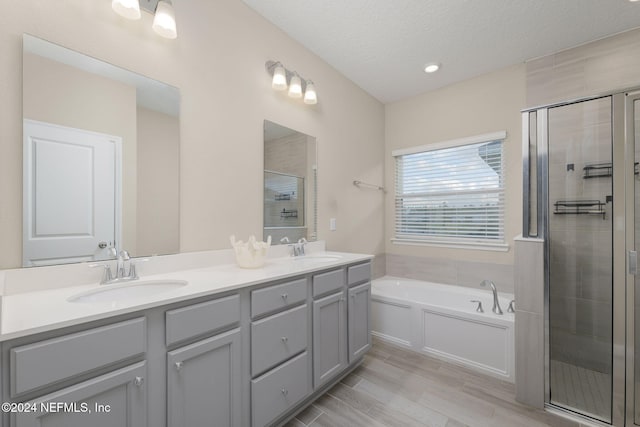 bathroom with separate shower and tub, vanity, and a textured ceiling