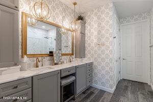 bathroom featuring a chandelier, wood-type flooring, vanity, and a shower with shower door