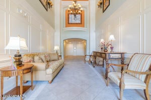 living room featuring a chandelier, light tile patterned floors, and a towering ceiling