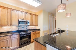 kitchen with sink, electric range, dark stone countertops, tasteful backsplash, and decorative light fixtures