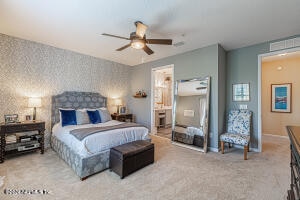 bedroom with ceiling fan, light carpet, and ensuite bath