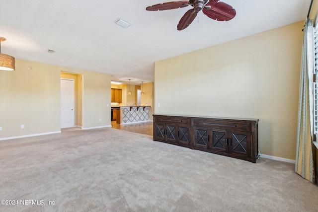 unfurnished living room featuring ceiling fan and light colored carpet