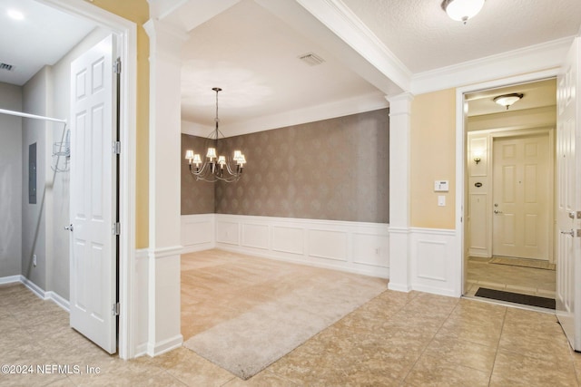 corridor with an inviting chandelier, decorative columns, a textured ceiling, carpet, and ornamental molding