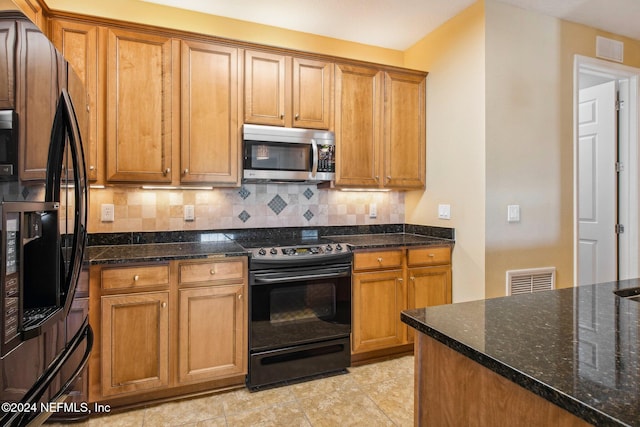 kitchen featuring dark stone counters, backsplash, light tile patterned floors, and black appliances