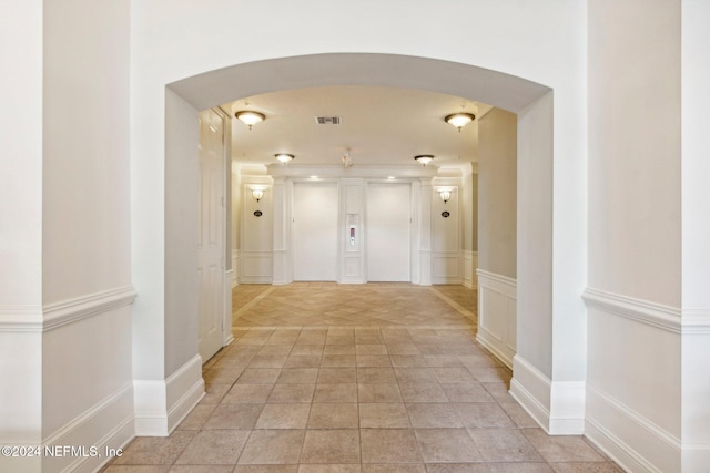 hallway with elevator and light tile patterned flooring