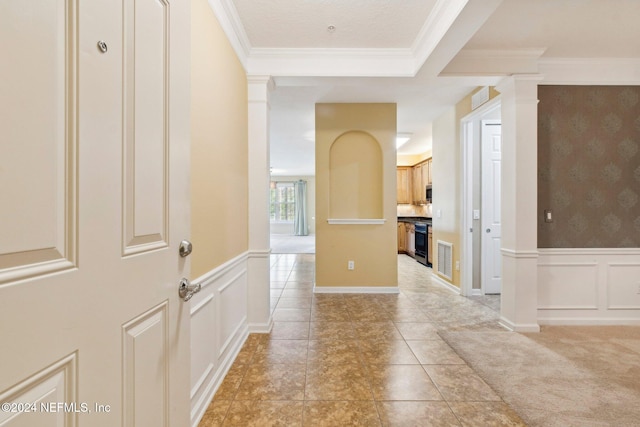 corridor with light colored carpet, crown molding, and decorative columns