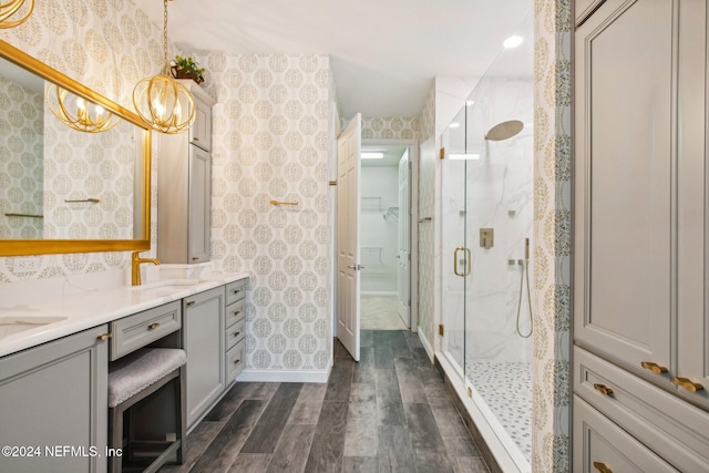 bathroom featuring an inviting chandelier, vanity, wood-type flooring, and walk in shower