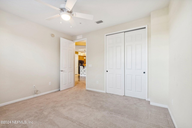 unfurnished bedroom featuring ceiling fan, a closet, and light colored carpet