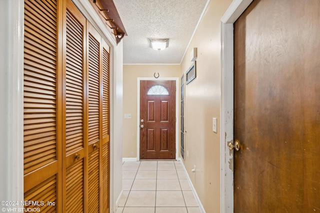 doorway to outside with a textured ceiling, crown molding, and light tile patterned flooring